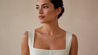 Mulher usando colar delicado com pequeno ponto de luz e roupa marfim