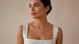 Mulher usando colar delicado com pequeno ponto de luz e roupa marfim