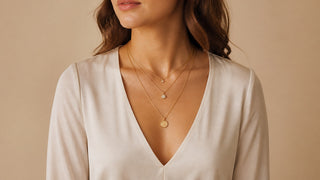Mulher usando três colares dourados delicados em comprimentos diferentes