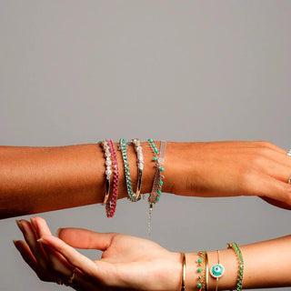 Mix de pulseiras banhado a ródio da UNA Semijoias em composição nos pulsos femininos, com design sofisticado em fundo neutro