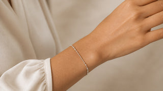 Pulso feminino usando pulseira prateada delicada