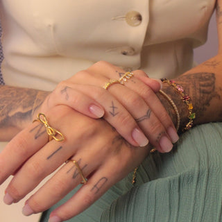 Anel liso quadrado banhado a ouro 18k da UNA Semijoias no dedo feminino, composição moderna com mix de anéis.