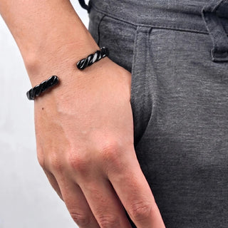Bracelete de aço preto rígido trançado da UNA no pulso, modelo unissex com design moderno e sofisticado