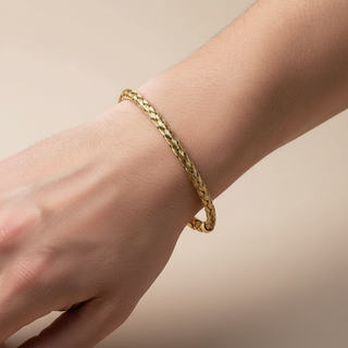 O Bracelete de Aço Dourado Masculino Rígido Trançado da UNA une acabamento dourado, textura trabalhada e estrutura resistente. A peça em aço inox tem brilho moderno e presença elegante para compor looks masculinos.