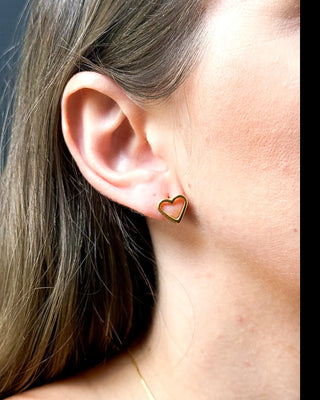Brinco delicado em formato de coração vazado banhado a ouro 18k da UNA Semijoias na orelha feminina em close lateral