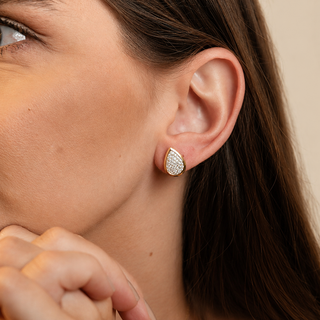 Par de brincos gota pequenos cravejados banhados a ouro 18k da UNA em fundo branco, com acabamento delicado na modelo