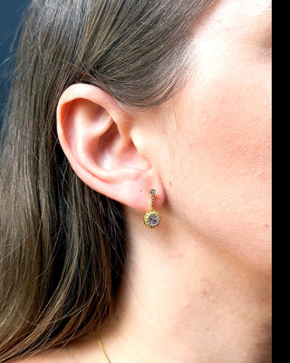 Brinco ponto de luz banhado a ouro 18k da UNA Semijoias na orelha feminina em close lateral, com zircônias cravejadas em destaque.