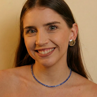 Choker riviera lilás banhada a prata 925 da UNA Semijoias no colo feminino, em close frontal, com brilho intenso das pedras azuis ao redor do pescoço