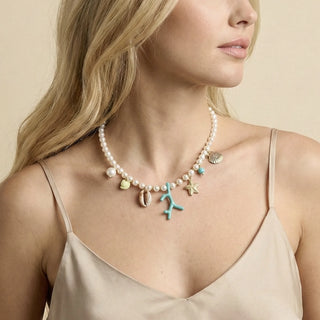 Choker de bijuteria fina com contas tipo pérola e pingentes do mar coloridos em resina e metal dourado da UNA Semijoias em fundo branco.
