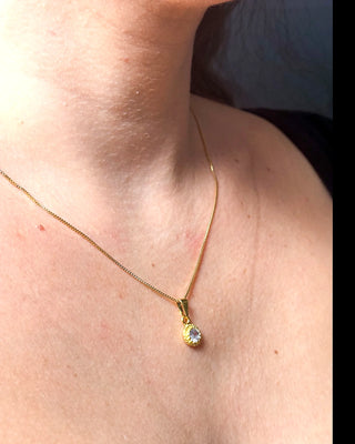Colar ponto de luz banhado a ouro 18k da UNA Semijoias no colo feminino em close, com pingente redondo cravejado em destaque.