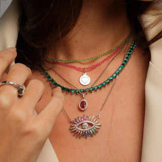 Colar riviera 3 pontas turmalina banhado a ródio da UNA Semijoias e Aço no colo feminino em close, com camada dupla de colares em destaque.