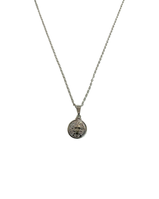 Colar São Bento banhado a prata 925 da UNA Semijoias em fundo neutro claro, com medalha religiosa redonda em destaque na corrente.