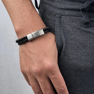 Pulseira de aço com couro e bolinhas preta da UNA no pulso, modelo unissex com design sofisticado para uso diário