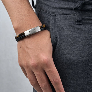 Pulseira de aço com couro e pedra olho de tigre da UNA no pulso, modelo unissex com design sofisticado para uso diário
Title da imagem: