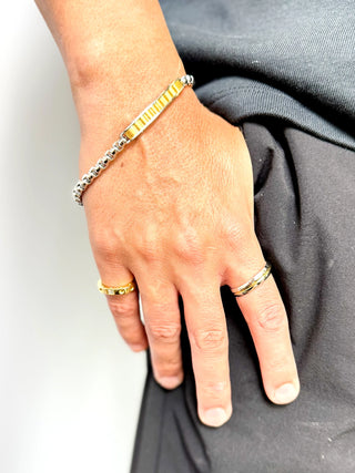 Pulseira masculina de aço inox com detalhe dourado da UNA Semijoias no pulso masculino em close, acessório moderno, antialérgico e de acabamento fino.