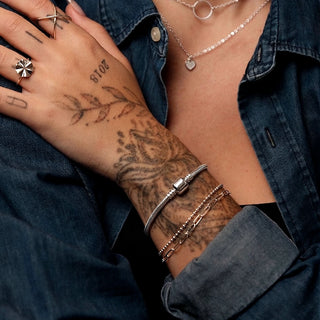 Pulseira berloque tradicional banhada a prata 925 da UNA no pulso feminino, em foto editorial com styling sofisticado