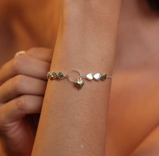 Pulseira com corações lisos e pingente central banhada a prata 925 da UNA Semijoias em fundo branco, em vista frontal.