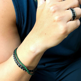 Pulseira masculina em aço inox black com detalhes verdes no pulso, com anéis em aço e colar combinando, em foto de lifestyle UNA Semijoias.