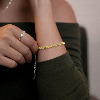 Pulseira riviera amarela banhada a prata 925 da UNA Semijoias no pulso feminino em close, com pedras amarelas e corrente ajustável em destaque.
