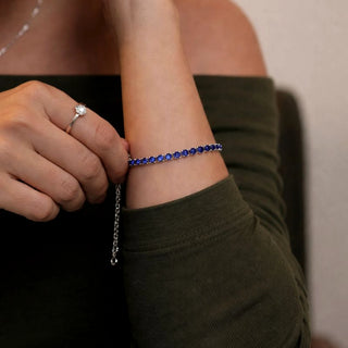 Pulseira riviera azul banhada a prata 925 da UNA Semijoias no pulso feminino, em close, com brilho delicado e corrente ajustável em destaque