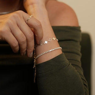 Pulseira riviera transparente banhada a prata 925 da UNA Semijoias em fundo branco, com extensor ajustável e fileira de pedras brilhantes.