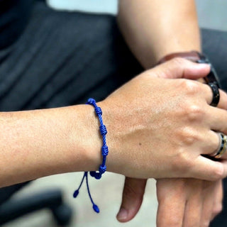 Pulseira artesanal azul de nozinhos da sorte da UNA no pulso, modelo unissex em fio de seda encerado