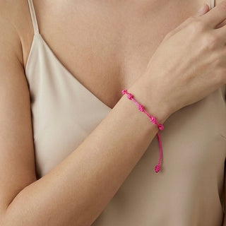 Pulseira verão nozinho da sorte rosa da UNA Semijoias em fundo branco, com cordão rosa ajustável e nós delicados distribuídos pela pulseira.