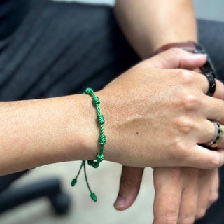 Pulseira artesanal verde de nozinhos da sorte da UNA no pulso, modelo unissex em fio de seda encerado